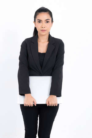 Portrait business woman holding laptop wearing a black suit at studio shot isolated on white background. Pretty female model. Confident professional office worker.の写真素材