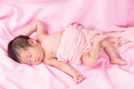 Portrait of a one month old sleeping, newborn baby girl on a pink blanket. Concept portrait studio fashion newborn.の写真素材