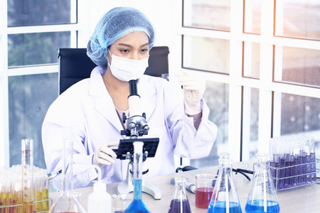 Scientist looking through a microscope in a laboratory. Young scientist doing some research.