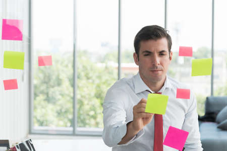 Businessman take notes at colorful chart on glass board is using the idea at his office, in the evening time.の写真素材