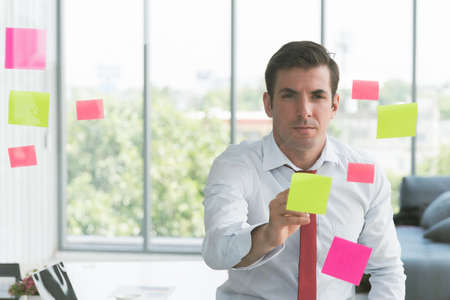 Businessman take notes at colorful chart on glass board is using the idea at his office, in the evening time.の写真素材