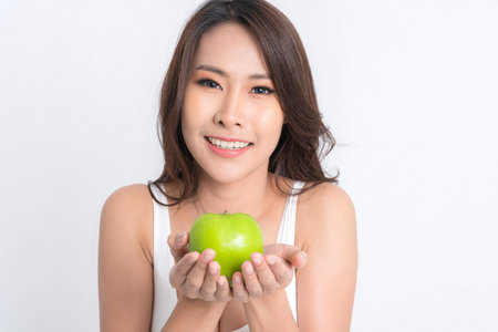Beautiful asian young woman healthy food wearing white underwear holding green apple with healthy food isolated on a white background.の写真素材