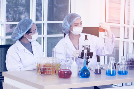 Laboratory two woman scientists Conduct Experiments. Chief Research Scientist Adjusts Specimen in a...