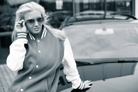 Woman sitting on car in front of car dealership の写真素材
