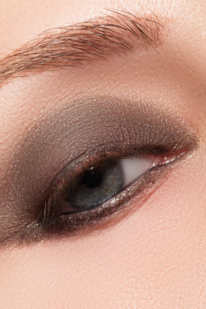 Close-up of blue woman eye with beautiful brown shades smokey eyes make-up. Modern fashion make-upの写真素材