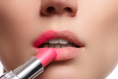 Part of attractive woman's face with fashion red lips makeup. Make-up artist apply pink lipstickの写真素材
