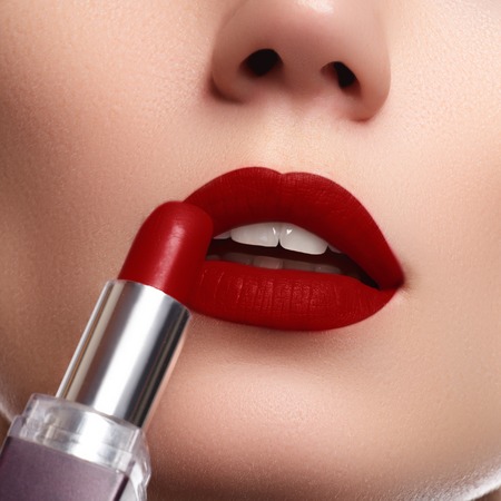 Extreme close up on model applying dark red lipstick. Makeup. Professional fashion retro make-up. dark red lipstick. Wine Lipsの写真素材