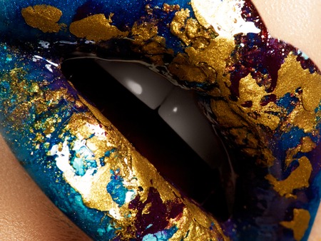 Fashion and beauty. Creative lip makeup. Artistic make-up. Beautiful plump lips. Shiny glossy lips with a different texture and colors: gold, aquamarine, blue and purple. Liquid gold and glitterの写真素材