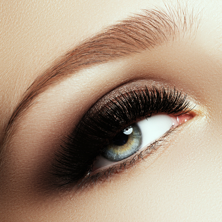 Beautiful macro shot of female eye with extreme long eyelashes and smoky makeup. Perfect eyebrows and long lashes. Cosmetics and make-up. Closeup macro shot of fashion eyes visageの写真素材