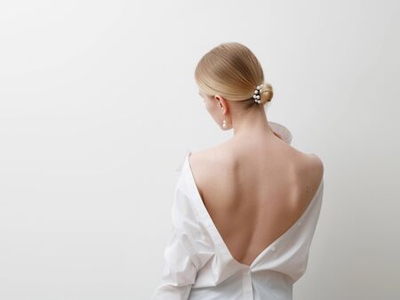 Minimalist photo, Fashionable girl in stylish summer things - white shirt. View from the back. Earrings, a ring . Street fashion , blogger style . Beauty . Minimalist Fashion clothesの写真素材