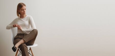 Fashionable girl in a white sweater and checkered pants . Natural lifestyle portrait of girl , emotional and fashion mood ,chic clothes and summer theme . Soft warm vintage color tone . Gold earringsの写真素材