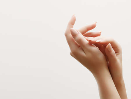 Hand skin care. Closeup of beautiful woman hands with light manicure on nails . Cream for hands and treatment.の写真素材