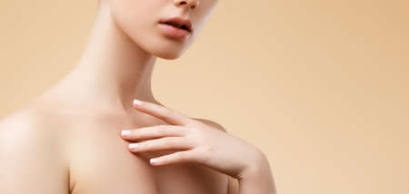 Beauty Spa Woman with perfect skin Portrait. Beautiful blond Spa Girl. Proposing a product. Gestures for advertisement. Beige backgroundの写真素材