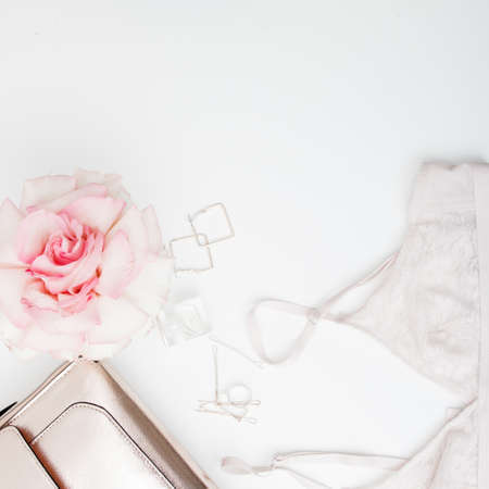 Minimal style. Minimalist Fashion photography. Decorative flat lay composition with cosmetics, womens accessories and flowers. Flat lay, top view on white backgroundの写真素材