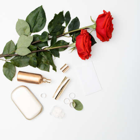 Decorative flat lay composition with cosmetics, womens accessories and flowers. Flat lay, top view on white backgroundの写真素材