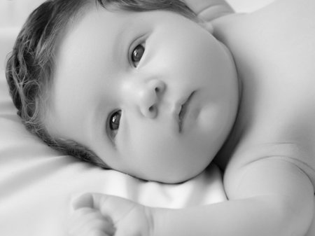Newborn baby in a wrap on white blanket. Beautiful portrait of little child girl 7 days, one week...