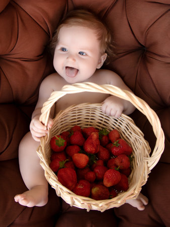 Happy baby have fun in the Park on a Sunny meadow with strawberry. Summer vacation concept. The emotionsの写真素材