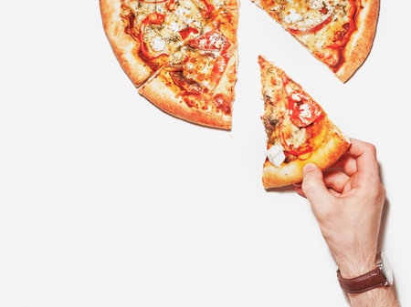 Slice of pizza in hand isolated on white. Top view on pizza. Concept for italian food, street food, fast food, quick bite. Bannerの写真素材