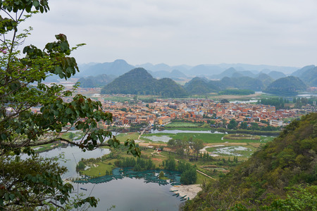 Colorful village between river and mountain range from viewpoint of peak mountain in cloudy day at Puzhehei, Yunnan, China.の写真素材