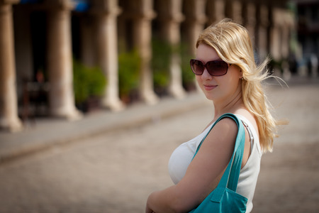 Young blonde woman in white shirt in a city at summerの写真素材