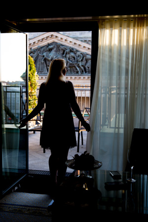 Young sexy blonde woman staying at balcony silhouette at sunsetの写真素材
