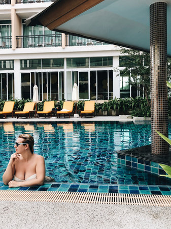 Young sexy blonde girl in swimming pool outdoors at luxury villa or resort