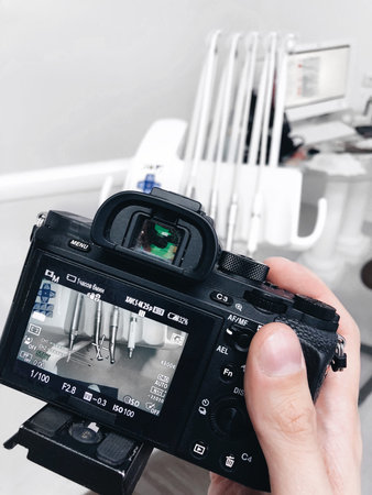 Photographer or videographer with dslr mirrorless camera in dental clinic shooting dentist backstage