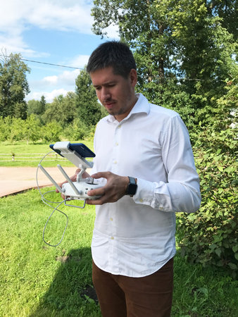 Man using drone, holding remote controller in hands in summer park