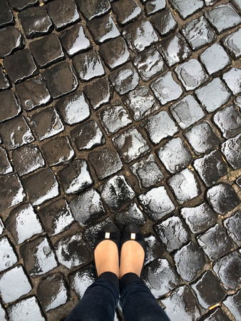 Woman legs on a street paving after rainの写真素材