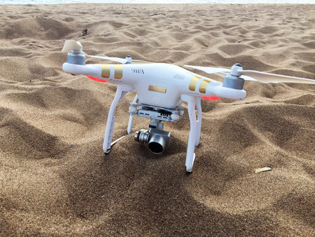 Professional drone quadcopter with digital camera on tropical beach.