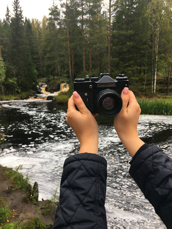 Woman taking selfie at Old retro film camera in a forest, wild nature landscapeの写真素材