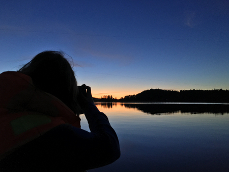Sunset at the lake, beautiful orange sky. Woman taking photoの写真素材