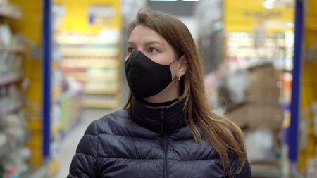 Woman in face protective mask in a supermarket shop cart at covid-19 coronavirus