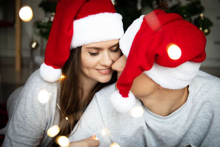 Beautiful young woman with long dark hair and a man in red and white Santa hatsの写真素材
