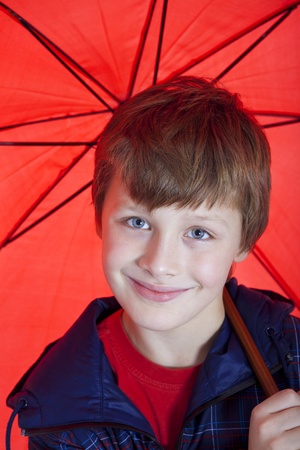 portrait of boy holding red umbrellaの写真素材