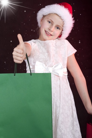 smiling girl in christmas hat holding shopping bagsの写真素材