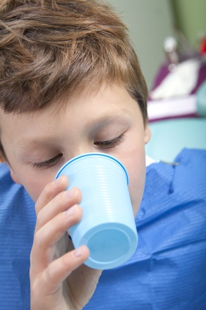 Young boy drinking water after dental operationの写真素材