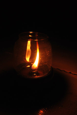 Vintage kerosene oil lantern lamp burning with a soft glow light and a candle flickering in the dark.の写真素材