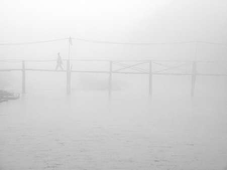 People standing on a wooden bridge in the mist.の写真素材