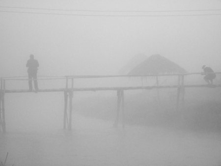 People standing on a wooden bridge in the mist.の写真素材