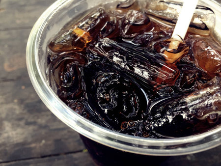 Cola Dark and sweet drink in a glass with ice on a wooden table.の写真素材