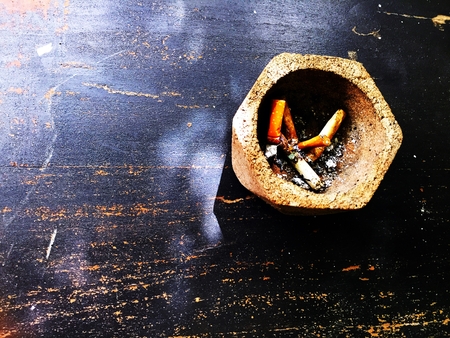 Ashtray shaped hexagons placed on a wooden table with cigarette butts inside.の写真素材