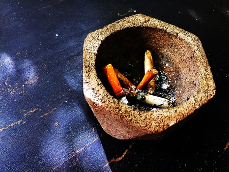 Ashtray shaped hexagons placed on a wooden table with cigarette butts inside.の写真素材