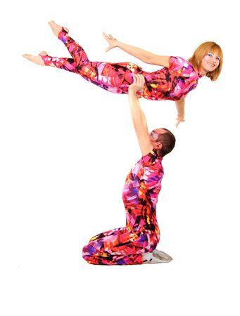 A pair of gymnasts in colorful stage costumes perform tricks on a white backgroundの写真素材