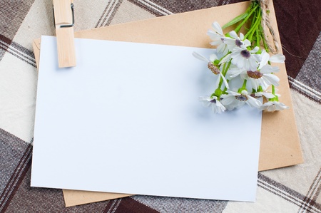 composition of the empty cardboard card with flowers and an envelope on fabricの写真素材