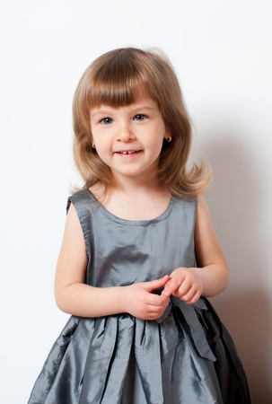 Smiling little girl in a beautiful dress standing in studioの写真素材