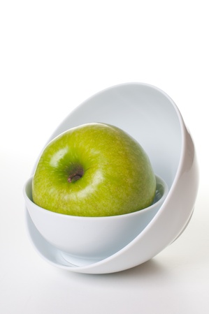 large green apple on a stack of white platesの写真素材