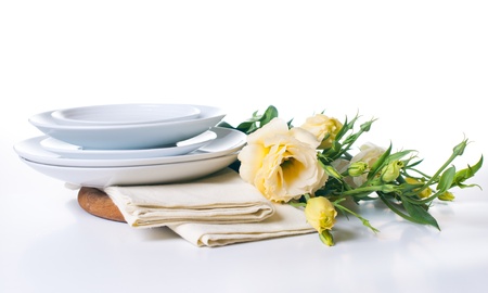 A stack of plates and a bouquet of yellow flowers on a white backgroundの写真素材