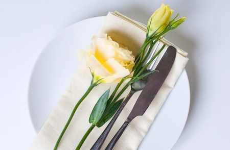 Plate, cutlery and yellow flower on a white backgroundの写真素材