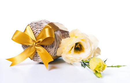Wicker box with yellow ribbon and a bouquet of eustomas on a white backgroundの写真素材